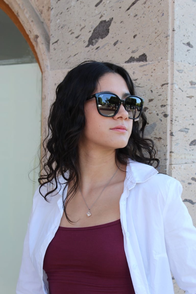Woman with long dark wavy hair wearing dark sunglasses